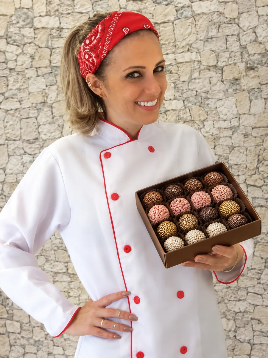 Julia, da Formiga Dondoca, sorrindo e segurando uma caixa de brigadeiros gourmet